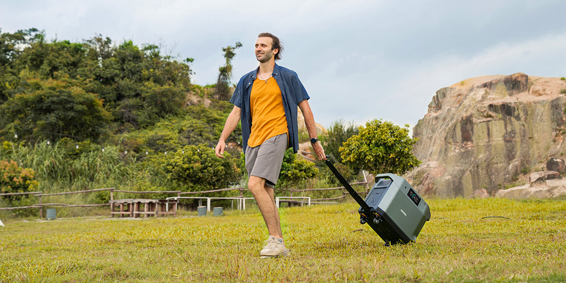 alt= In a field, a man walks alongside a portable power station.